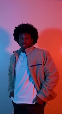 a man in a jacket standing in front of a colorful wall