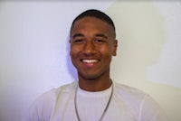 a young man wearing a white shirt and a necklace