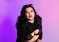 a woman in black lingerie posing in front of a purple background