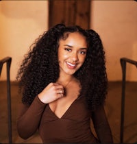 a young woman with curly hair posing for a photo