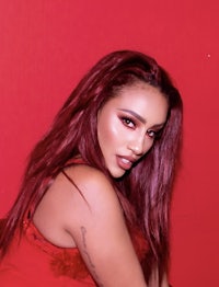 a woman with red hair posing in front of a red wall
