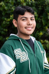a young man wearing a green and white jacket